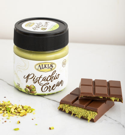 Jar of Alkis Pistachio Cream with a chocolate bar on a white surface