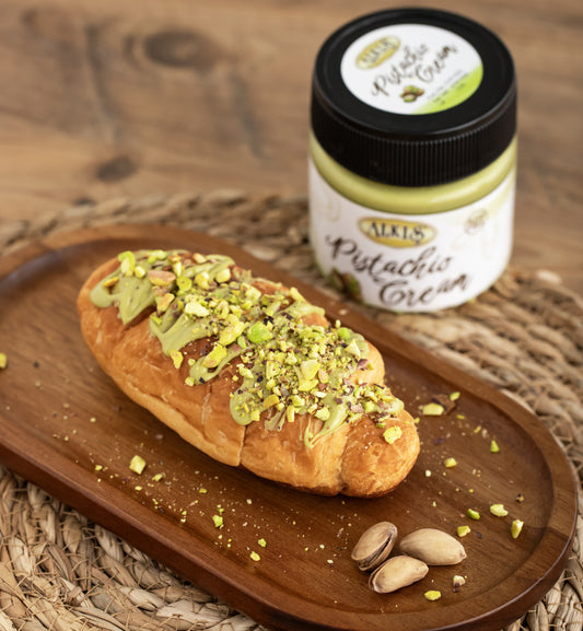 Pistachio cream on a pastry with a jar of pistachio cream on a wooden surface